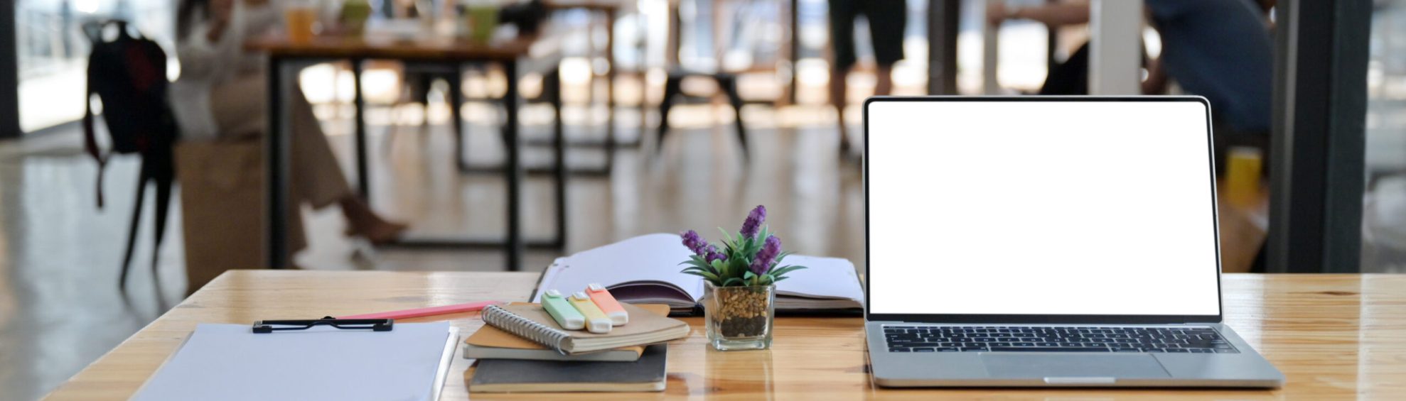 Cropped shot of laptop, notes and office supplies on a wooden desk in a comfortable shared workspace.